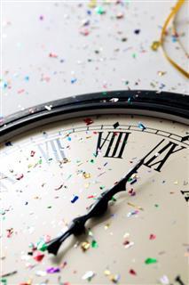 Clock showing midnight, with scattered confetti