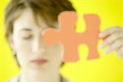 Woman with eyes closed holding jigsaw piece