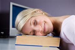 Woman, smiling and eyes closed, with head on a book