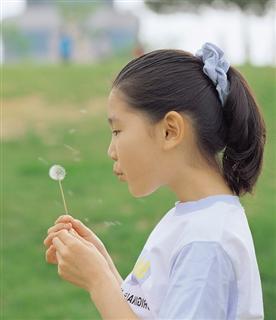 Girl blowing a dandelion clock